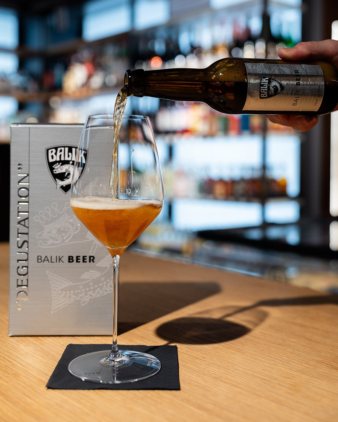 BALIK Beer wird in ein Glas eingeschenkt, daneben die Verpackung