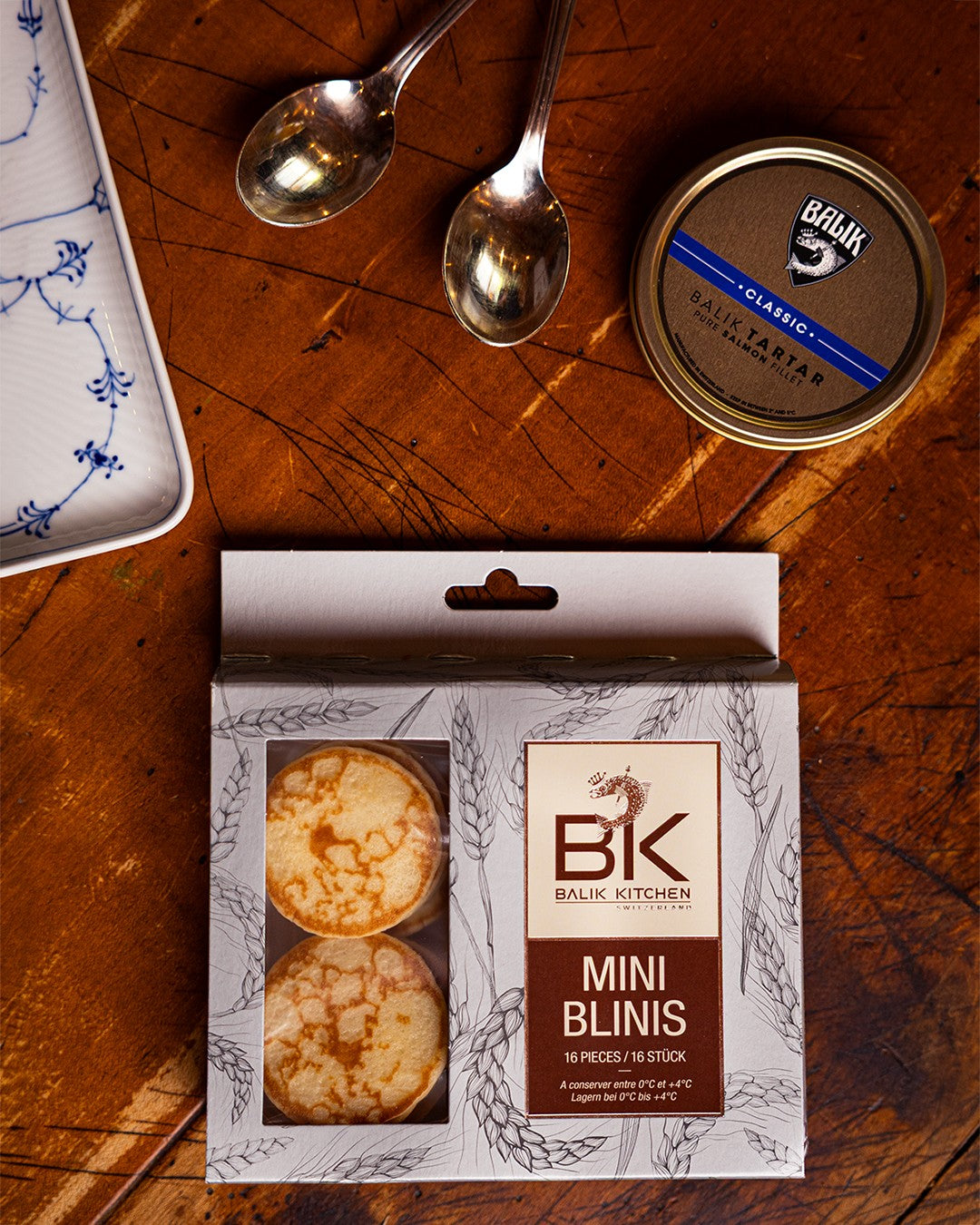 BALIK KITCHEN Mini Blinis auf einem Holztisch, daneben BALIK Tartar