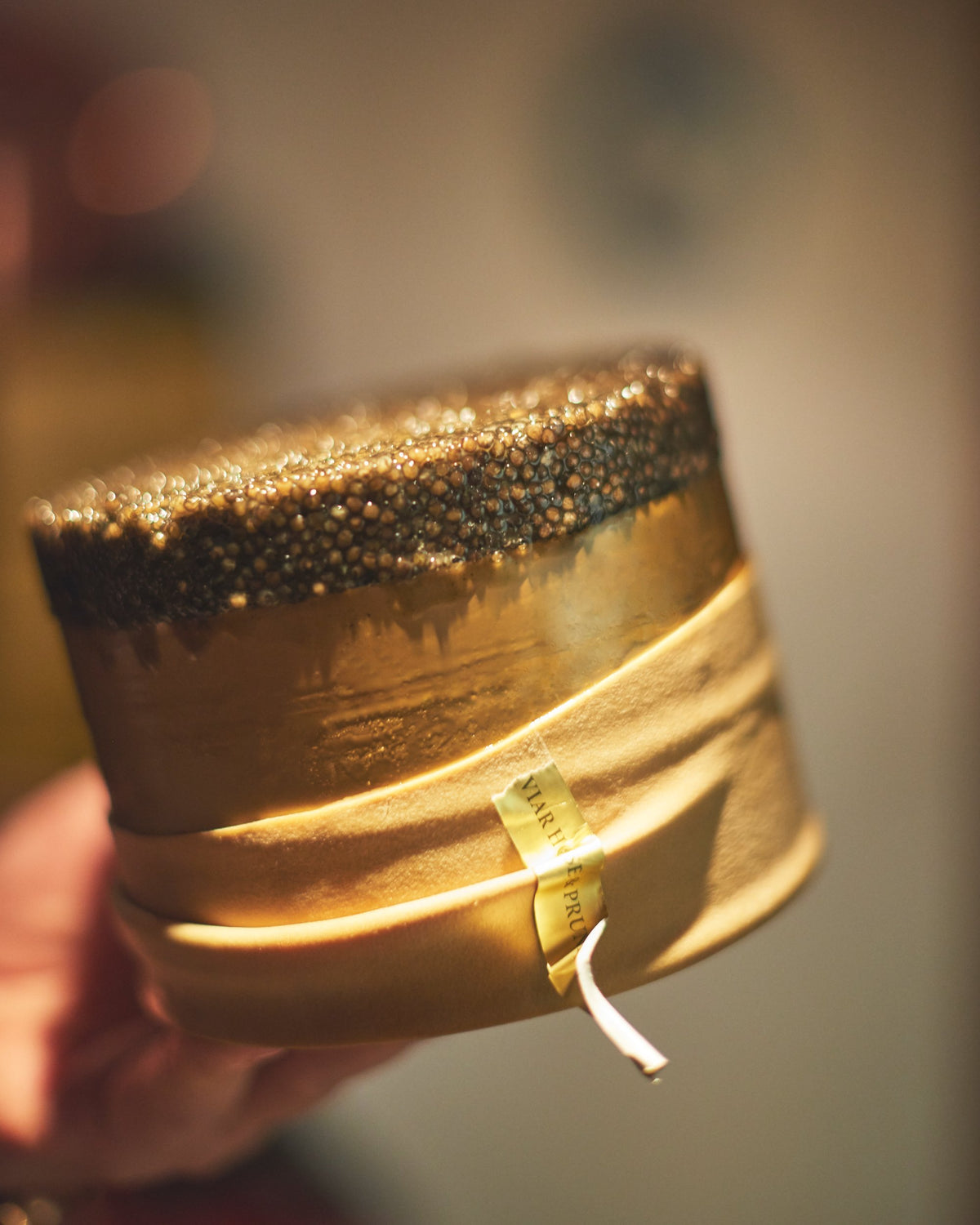 Volle Kaviardose mit goldenem Band, in der Hand gehalten