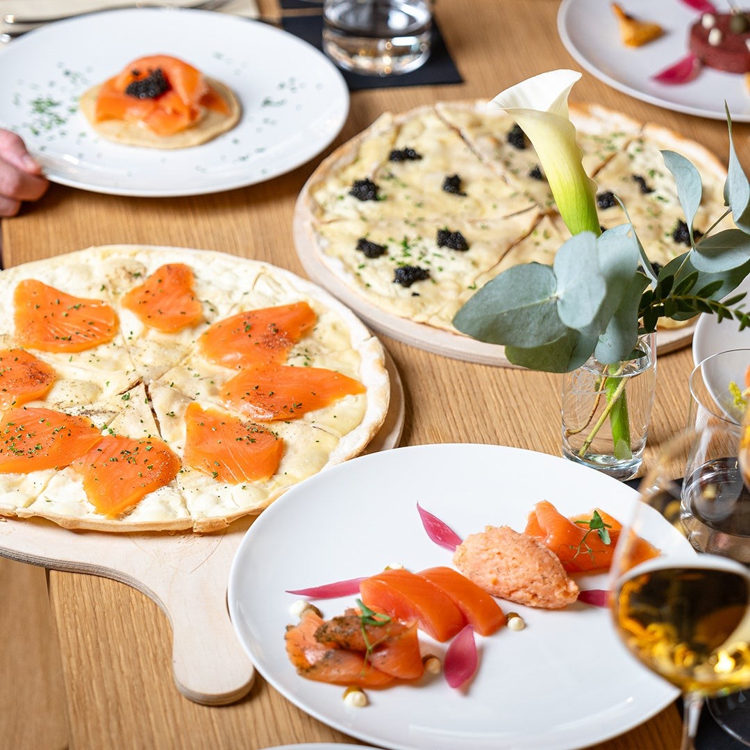 Gedeckter Tisch mit Flammkuchen mit Lachs und Kaviar, Blini und BALIK Tartar